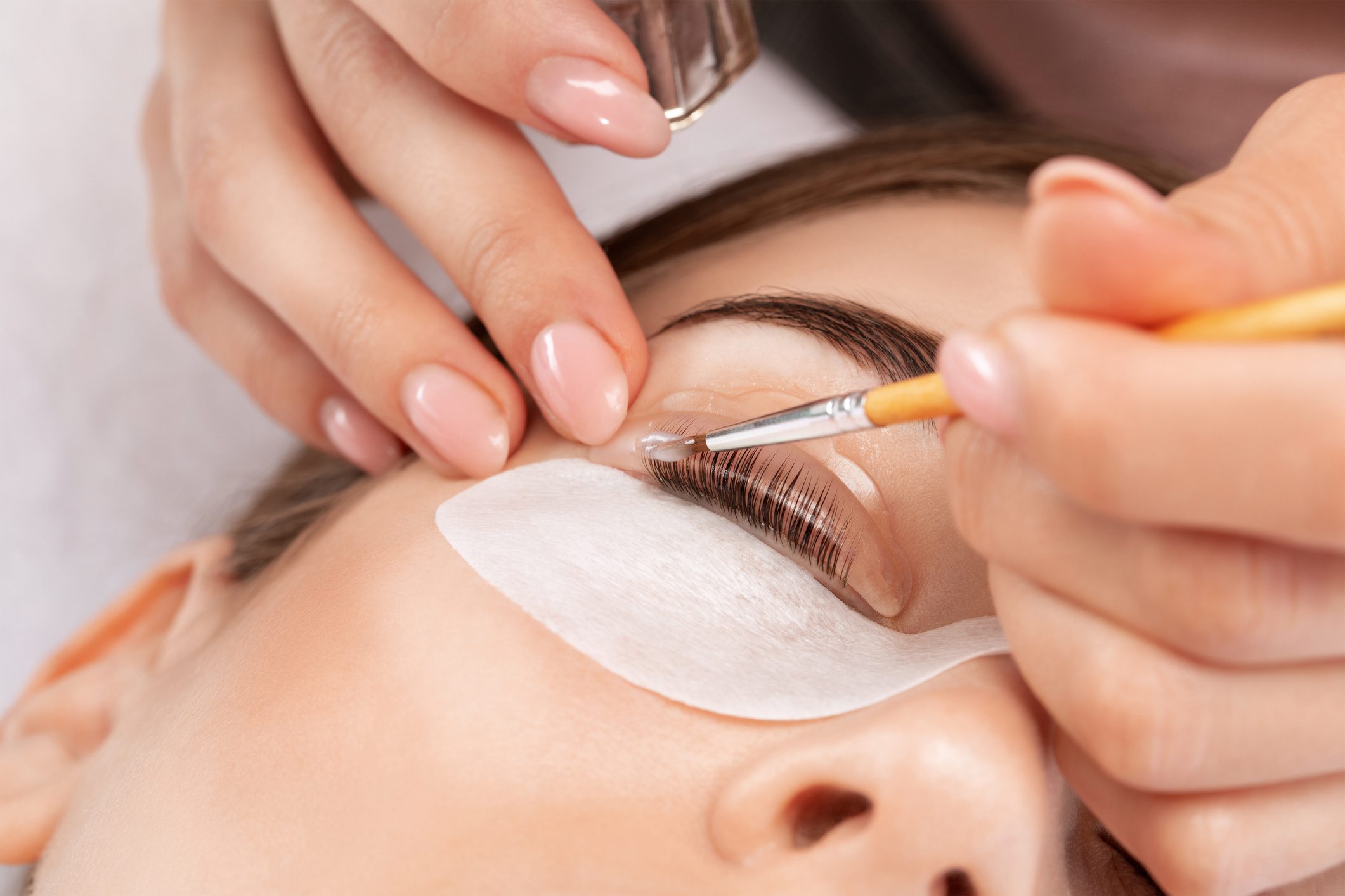 Applying eyelash extensions with precision on closed eyes.