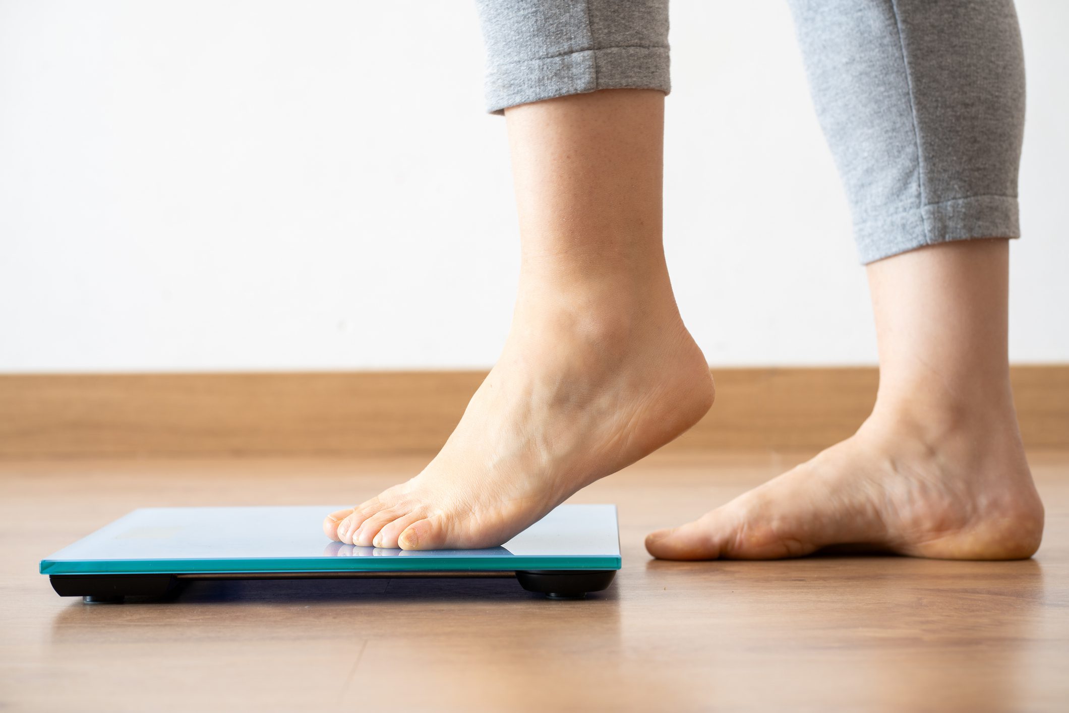 Person stepping onto a digital weighing scale barefoot.