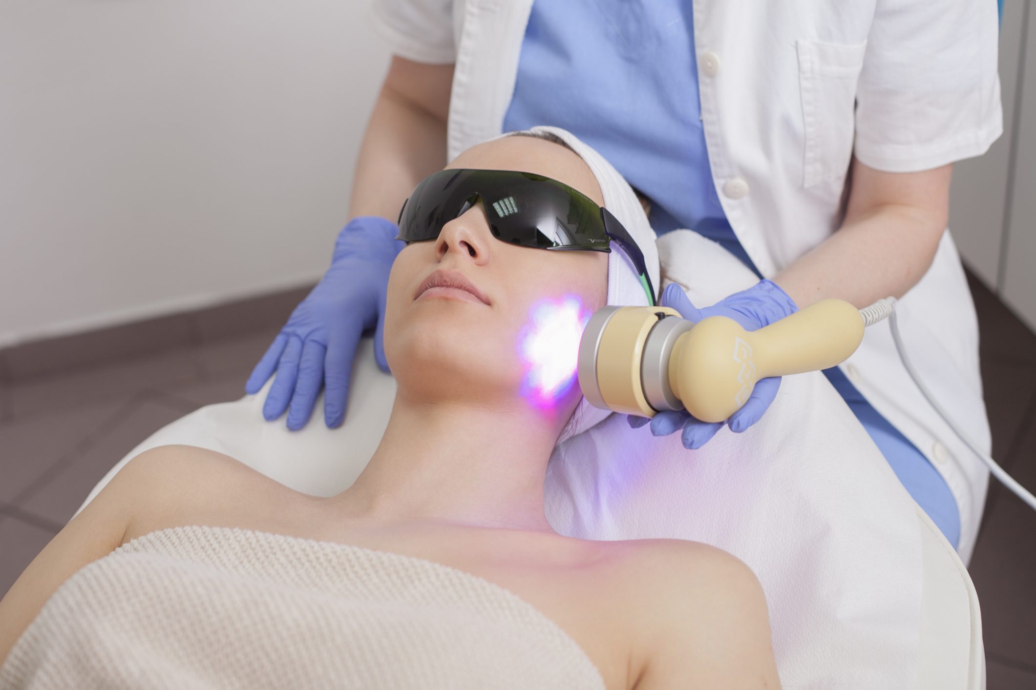 Man receiving laser facial treatment while wearing protective goggles.