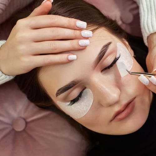 cosmetologist removes glue cotton strip under eye. Eyelash extension procedure