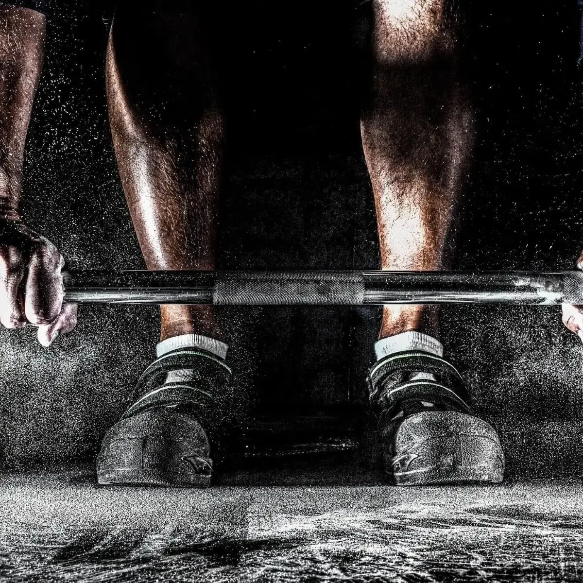 Close-up of chalky hands on barbell