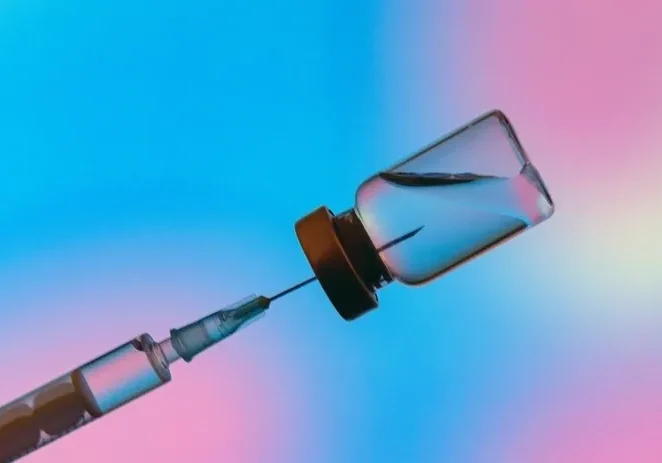 Syringe and vial against colorful background.