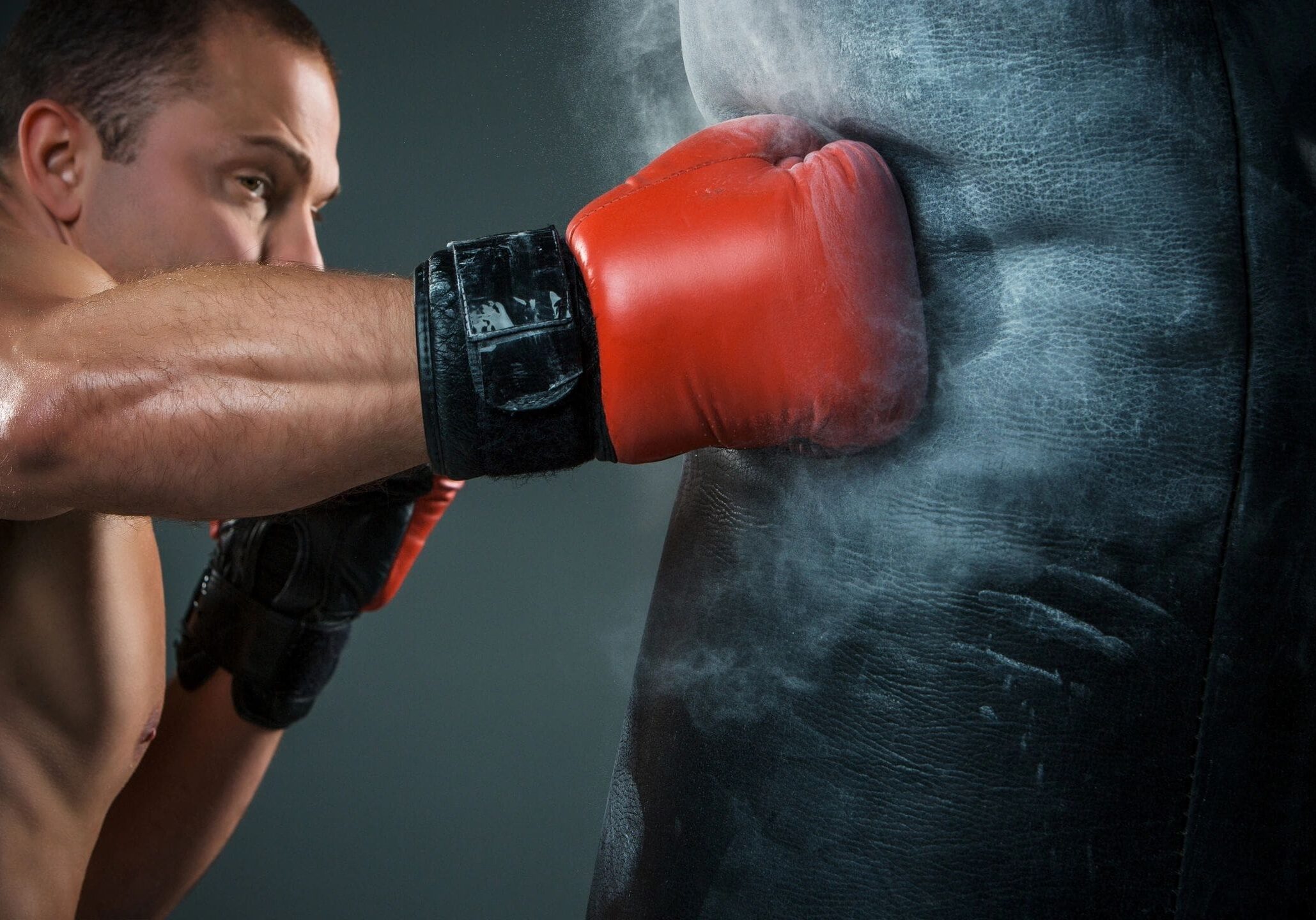 Boxer punching a heavy bag with gloves.
