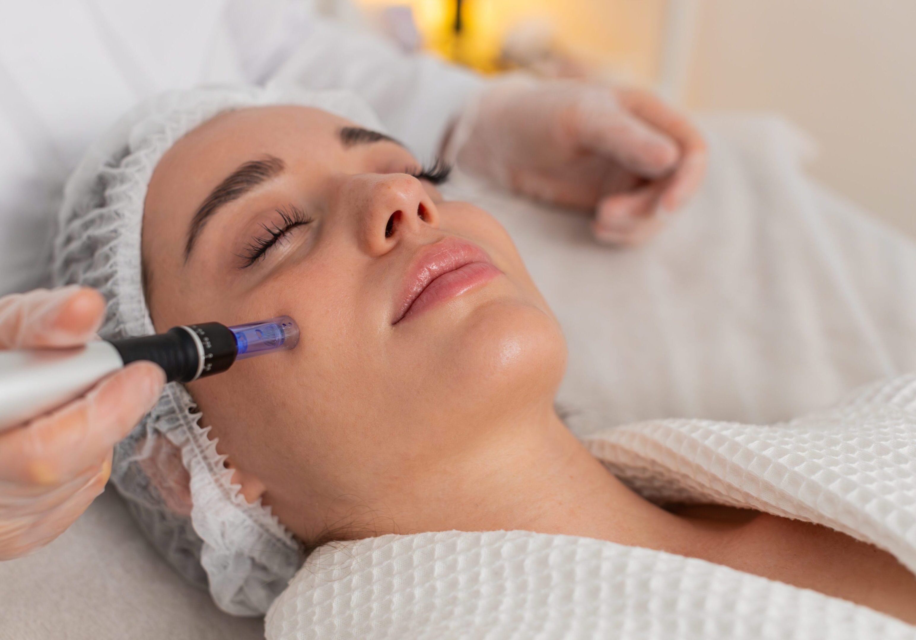 Woman receiving a facial treatment with a skincare device.