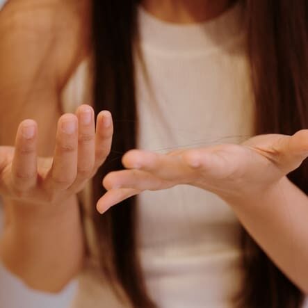 Asian woman noticing hair loss while combing her hair.