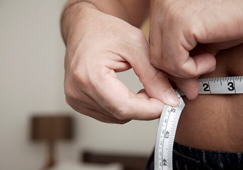 Person measuring waist with a tape measure.